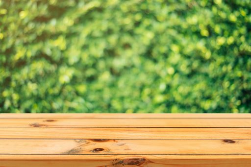 A wooden table surface with a vibrant green garden background in soft focus.