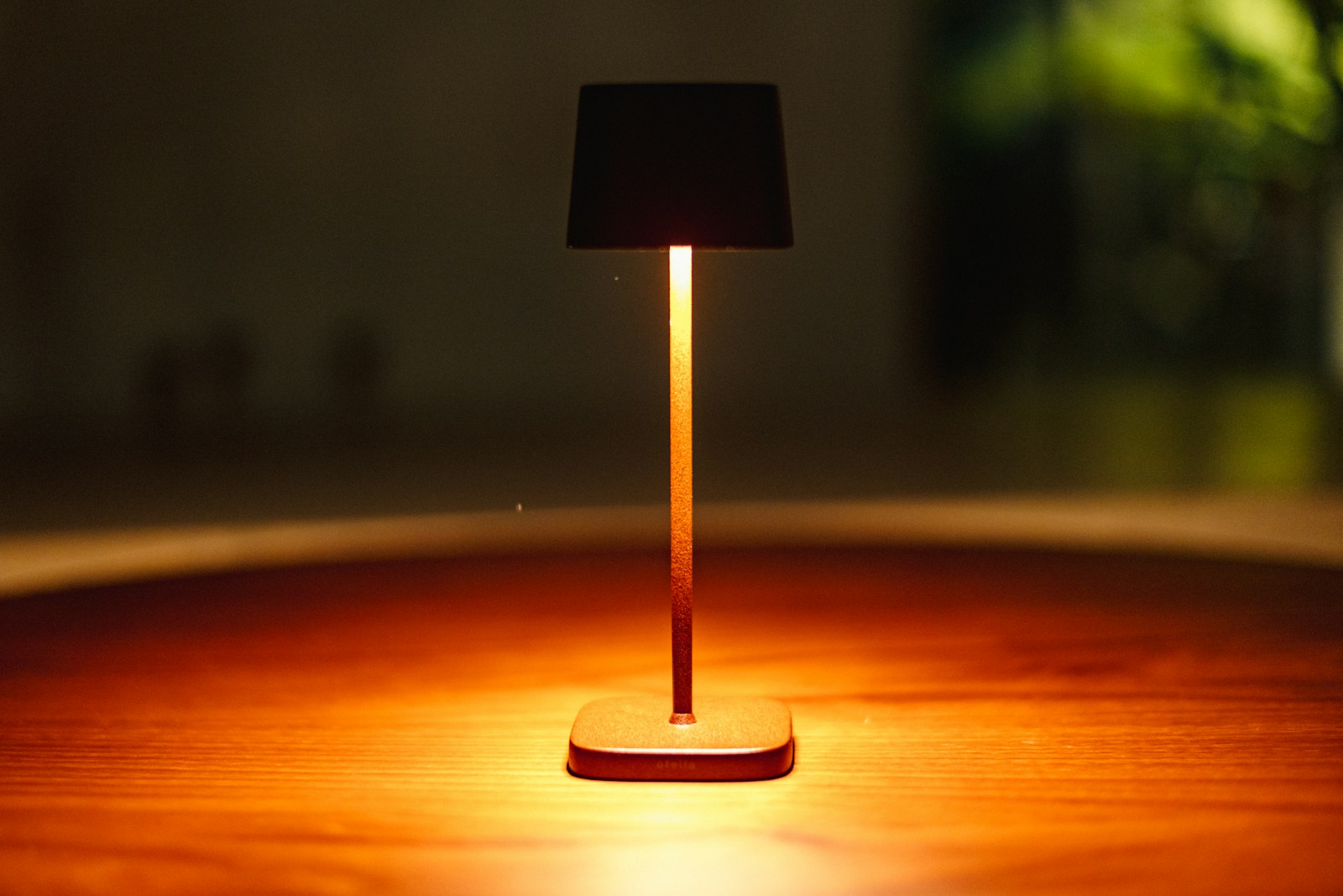 A small lamp illuminates a wooden table.