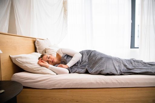 Eclectische slaapkamer met fluwelen sprei, ruw houten hoofdbord en gelaagde patronen op kussens en vloerkleed