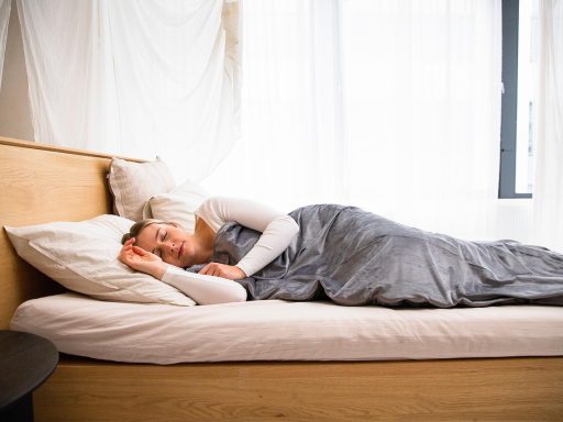 Eclectische slaapkamer met fluwelen sprei, ruw houten hoofdbord en gelaagde patronen op kussens en vloerkleed