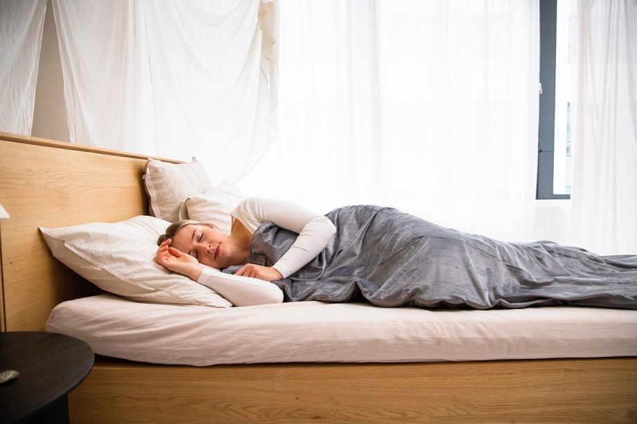 Eclectische slaapkamer met fluwelen sprei, ruw houten hoofdbord en gelaagde patronen op kussens en vloerkleed