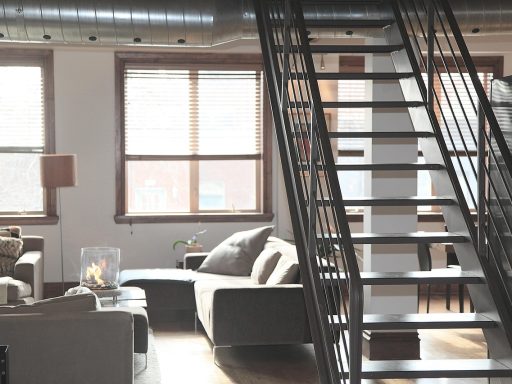 Moderne tussenverdieping in een loft met stalen balustrade en houten vloer boven een open woonkamer