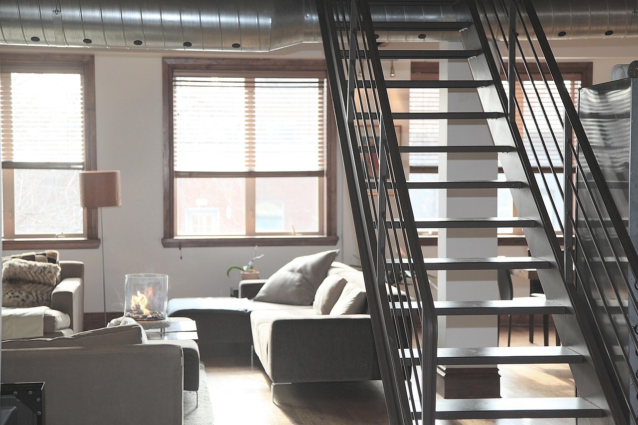 Moderne tussenverdieping in een loft met stalen balustrade en houten vloer boven een open woonkamer