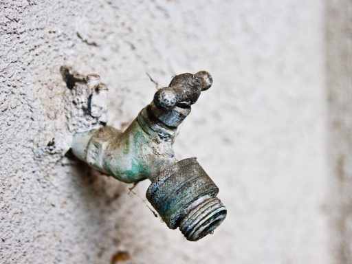 Een vorstvrije buitenkraan gemonteerd op een bakstenen muur met een rozet eromheen
