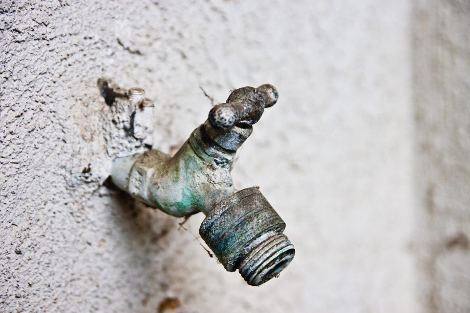 Een vorstvrije buitenkraan gemonteerd op een bakstenen muur met een rozet eromheen